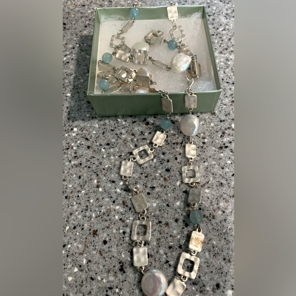 Long, silver tone geometric shape necklace with aqua accents.